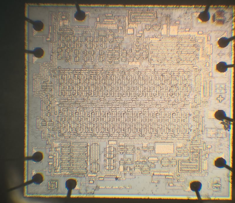 Exposed die after decapsulation, showing the full die surface and surrounding package structure